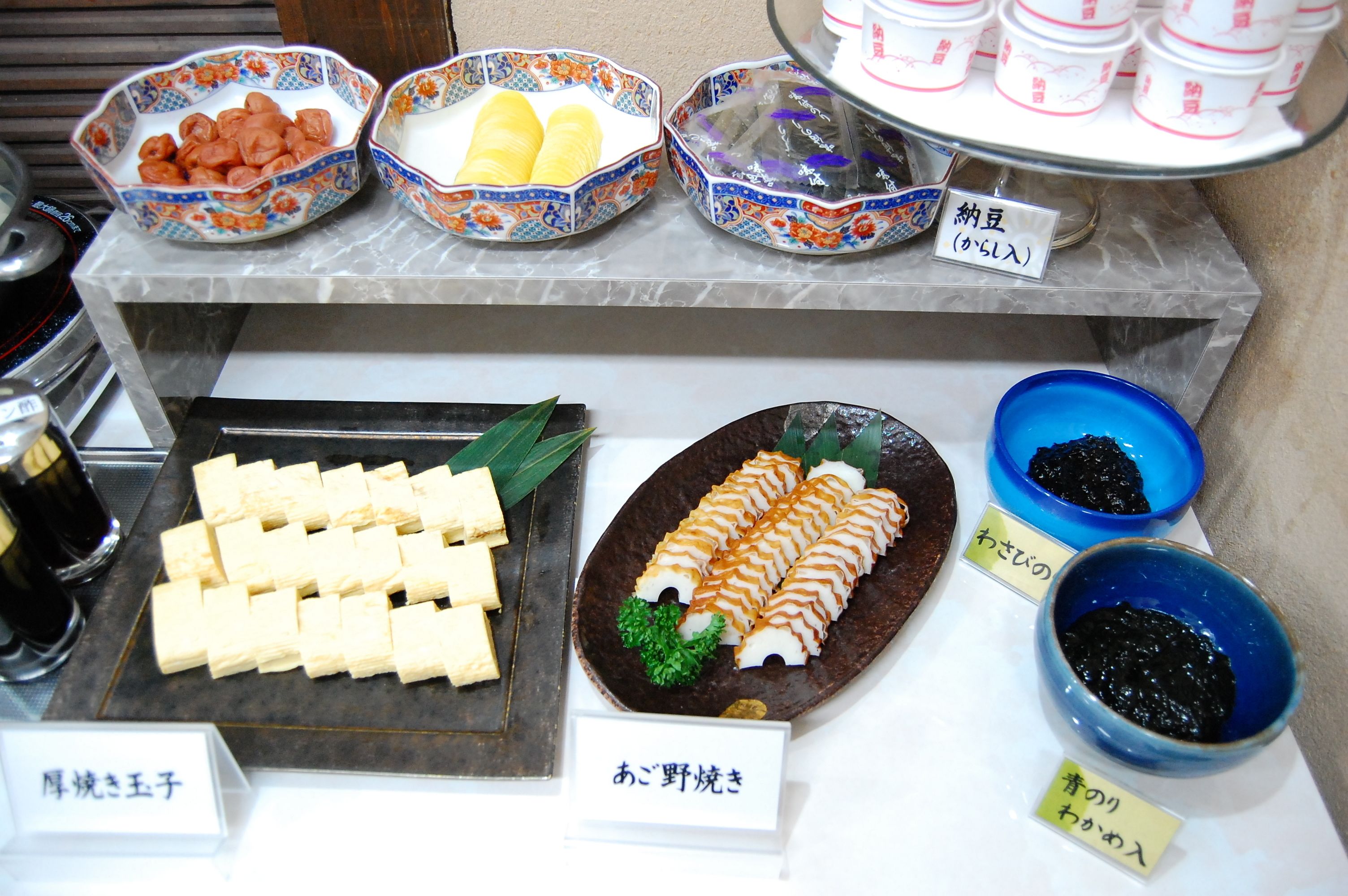 A buffet with various dishes including tofu, sashimi, and pickled vegetables.
