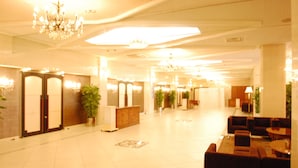Um hall amplo com lustre, área de estar e balcão de recepção.