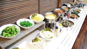 Buffet com diversos pratos, incluindo brócolis, vagem e arroz.