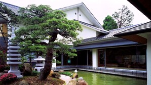 Un jardín japonés tradicional con un estanque, rocas y un pino.