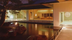 Una casa moderna con piscina, ventanas amplias y un interior tradicional japonés.