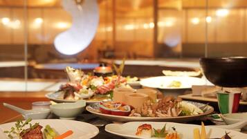 A dining table with various dishes, including meat, vegetables, and a bowl of mushrooms.