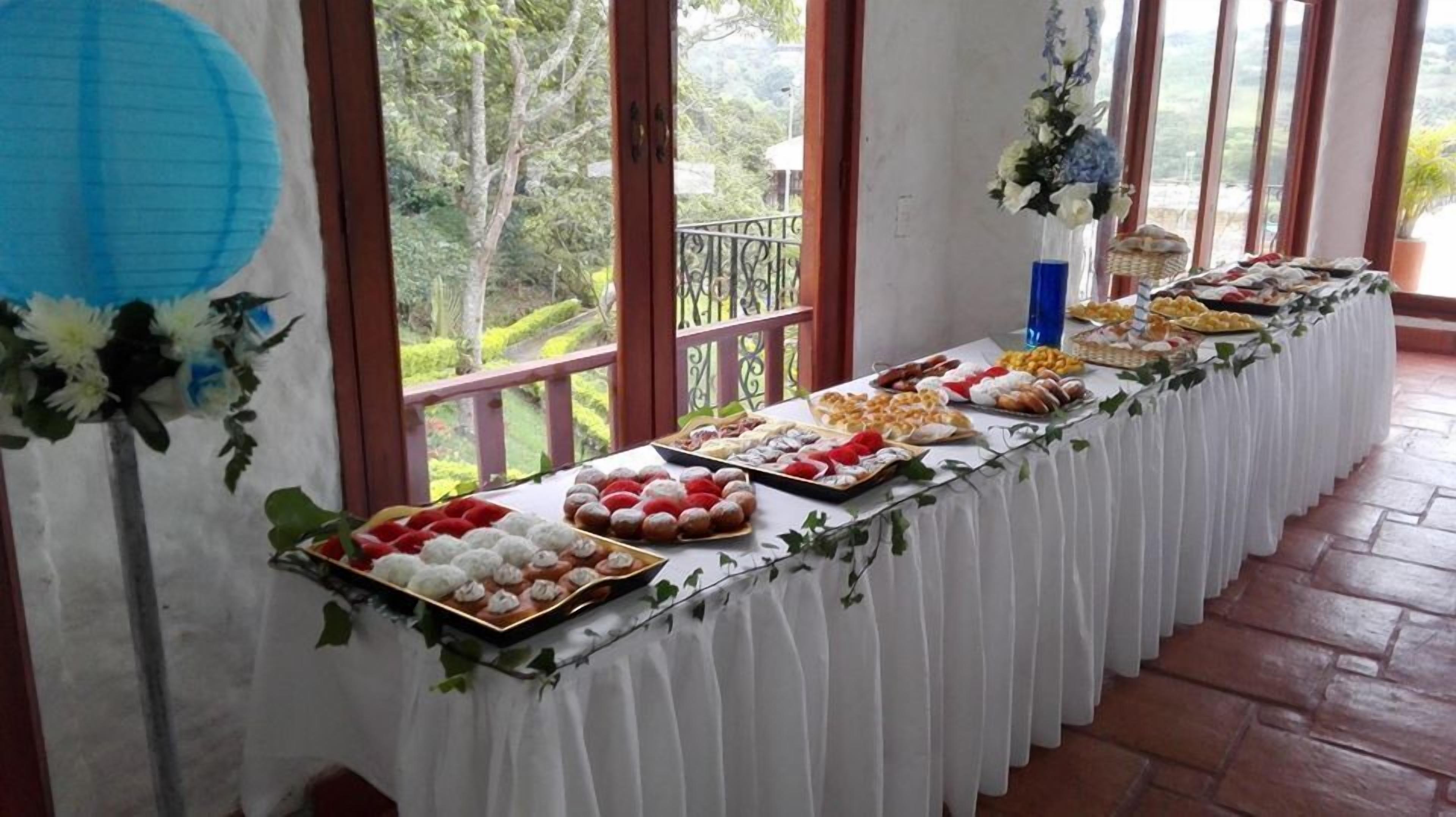 A buffet table with various food items, set up in a room with large windows and a balcony.