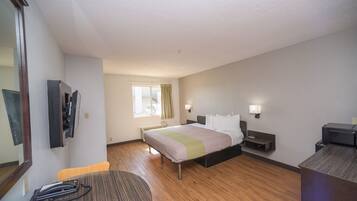 A hotel room with a bed, bedside tables, a desk, a chair, a telephone, and a window with curtains.