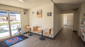 A hotel lobby with a reception desk, a seating area with four chairs and a table, and a large glass door leading outside. - Motel 6 New Iberia, LA (New Iberia)