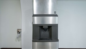 A stainless steel water dispenser with a black base, located in a room with white walls and a tiled floor. - Motel 6 New Iberia, LA (New Iberia)