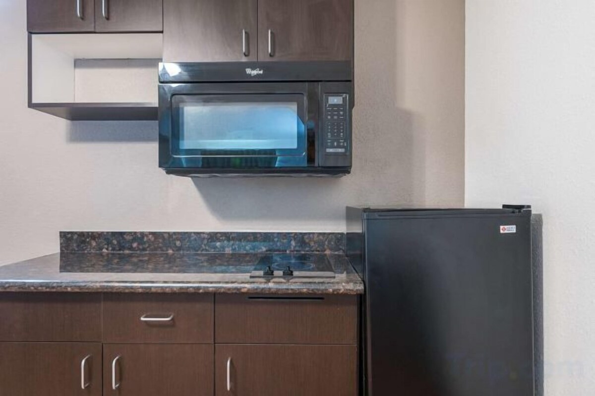A kitchen with a microwave, a refrigerator, and wooden cabinets.
