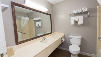 A bathroom with a sink, mirror, toilet, and towel rack.