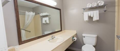 A bathroom with a sink, mirror, toilet, and towel rack.