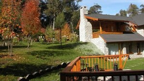 Una cabaña de piedra con terraza de madera y chimenea de piedra.