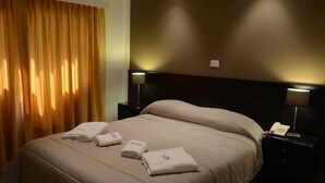 A hotel room with a bed, two bedside tables, a lamp, and a window with curtains. - Posta del Viajante (Mar del Plata)