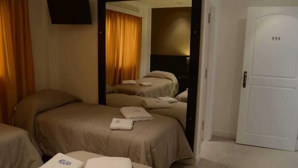 A hotel room with two beds, a TV, and a door marked with the number 604. - Posta del Viajante (Mar del Plata)