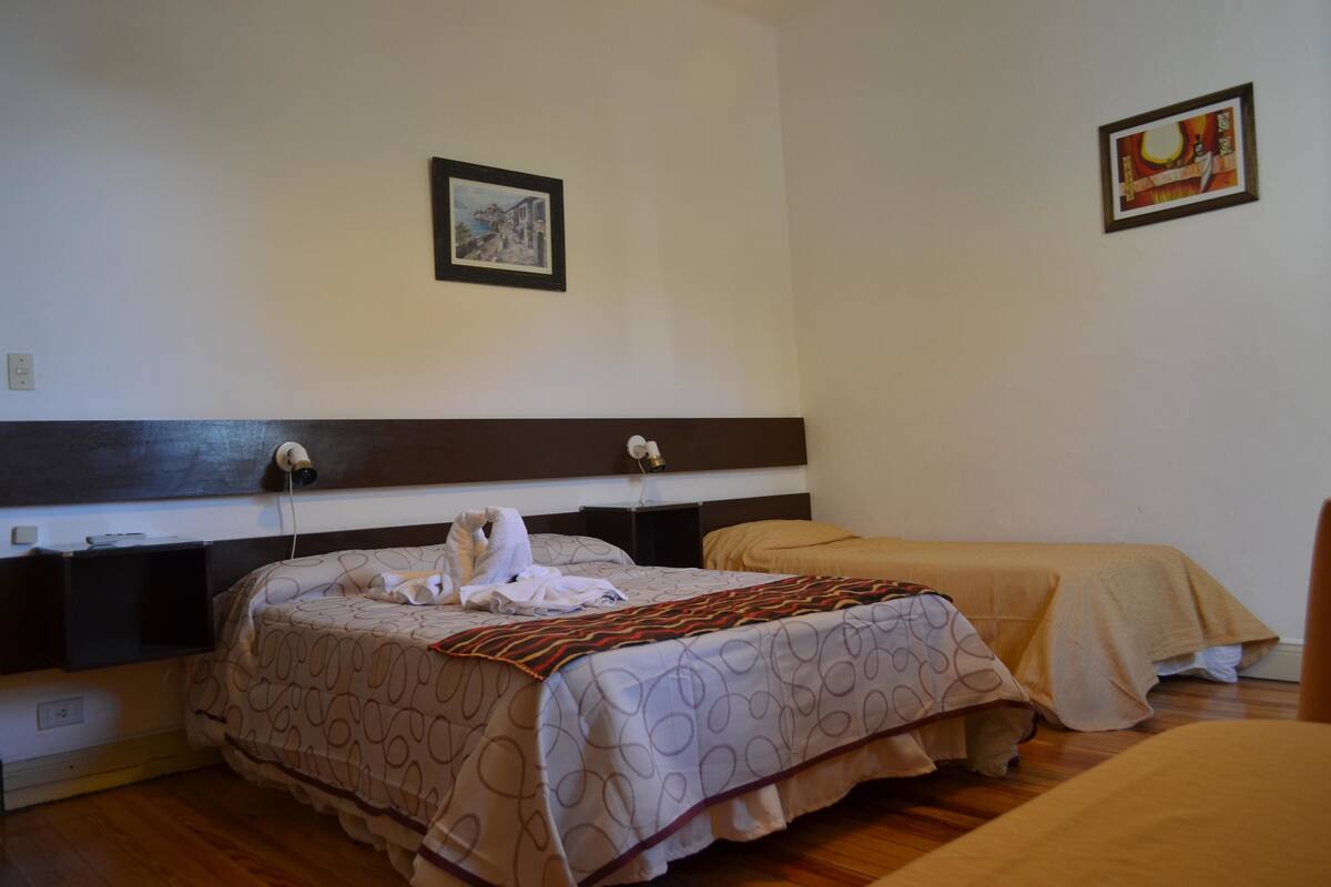 Ein Hotelzimmer mit Bett, Nachttisch, Wandlampe und einem gerahmten Bild an der Wand.