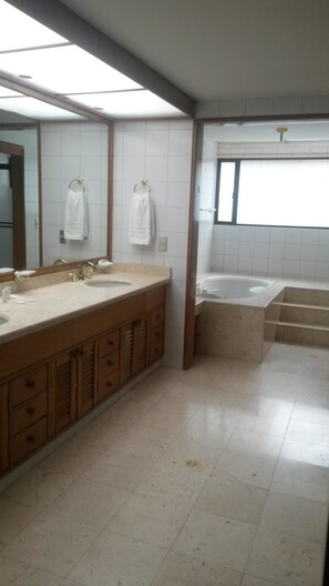 A bathroom with a large vanity, a bathtub, and a window. - Nogal Charlotte (Bogota)