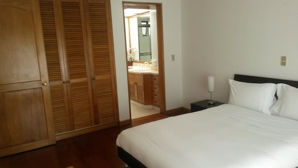 Un dormitorio con cama, mesita de noche, espejo y armario de madera.