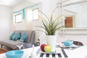 A dining area with a white table, blue bowls, a potted plant, and a glass of water.