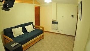 A small, cozy room with a single bed, a bedside table, and a wall-mounted heater. - Adamo Apart (San Rafael)