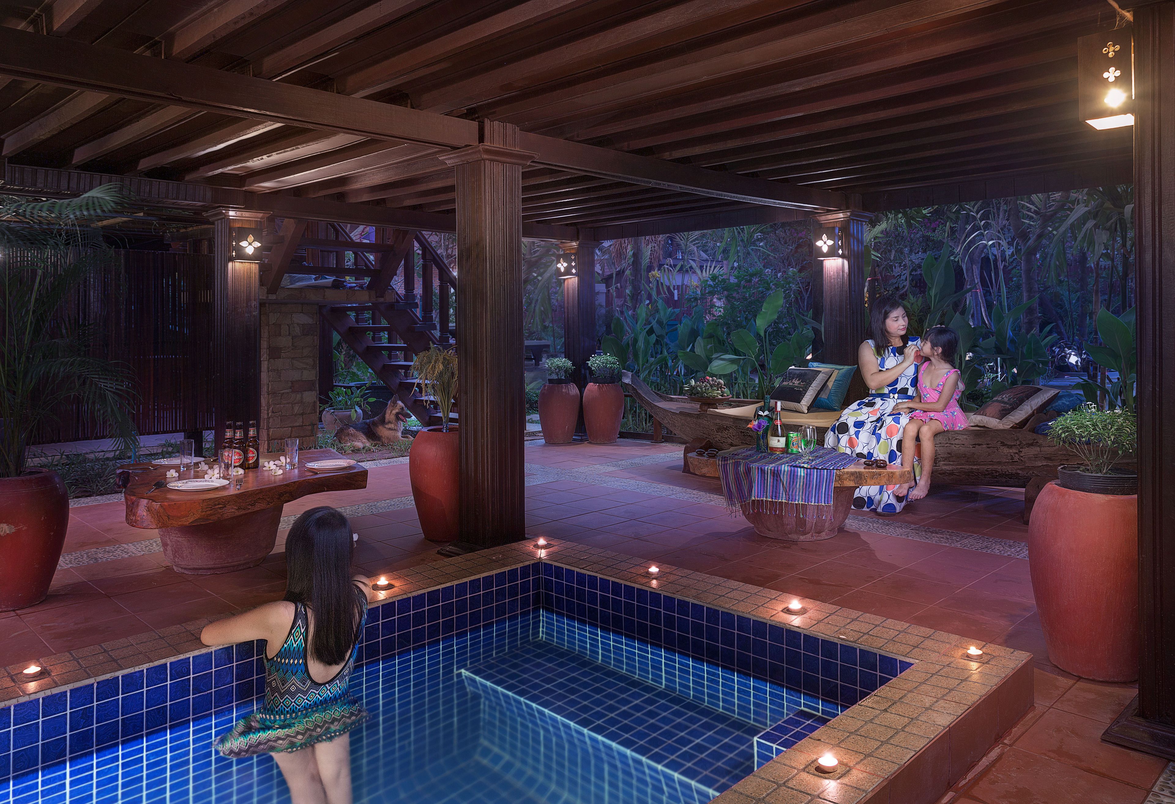 A pool area with a tiled floor, a wooden deck, and a seating area with a table and chairs.
