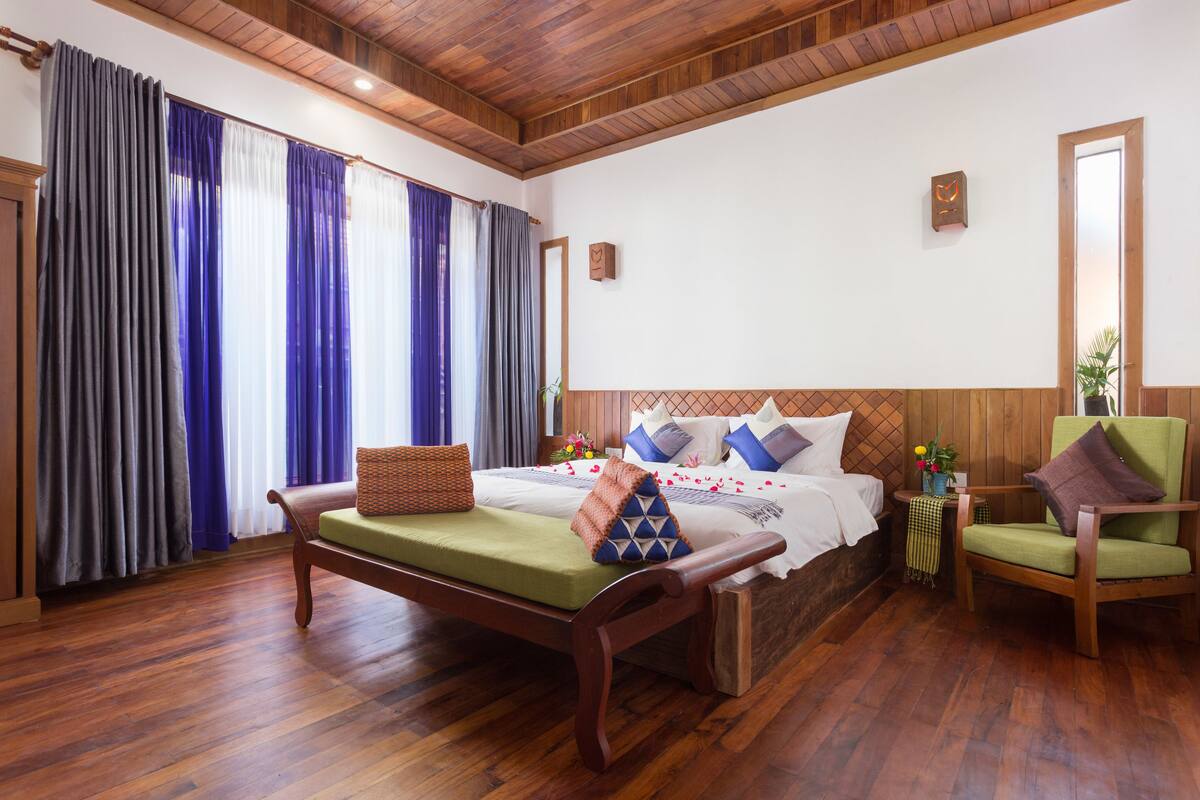Ein Zimmer mit Holzwänden, einem Bett, einer Bank und einem Sessel.