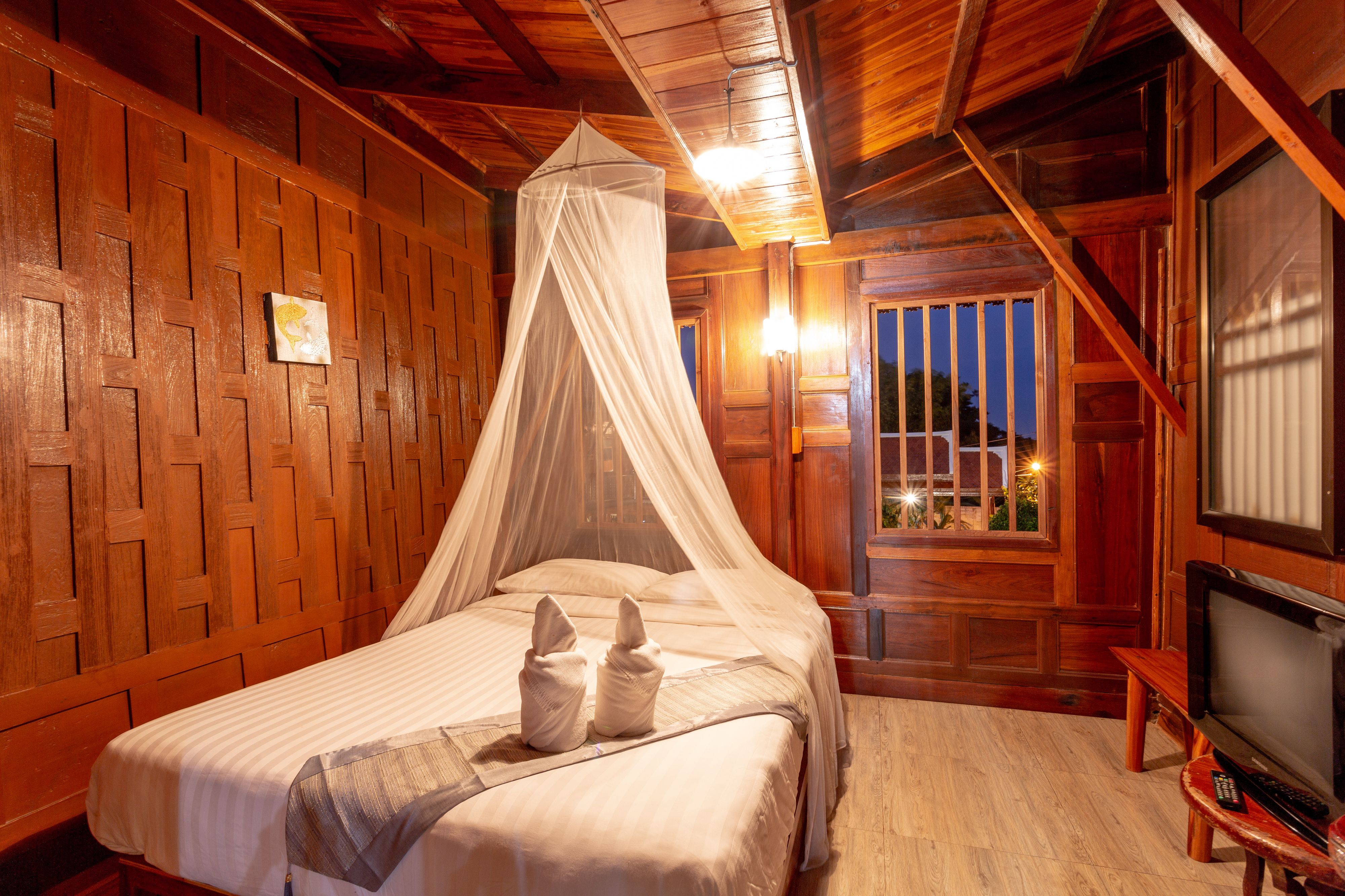 Una habitación de madera con una cama, un televisor y una ventana con vistas.