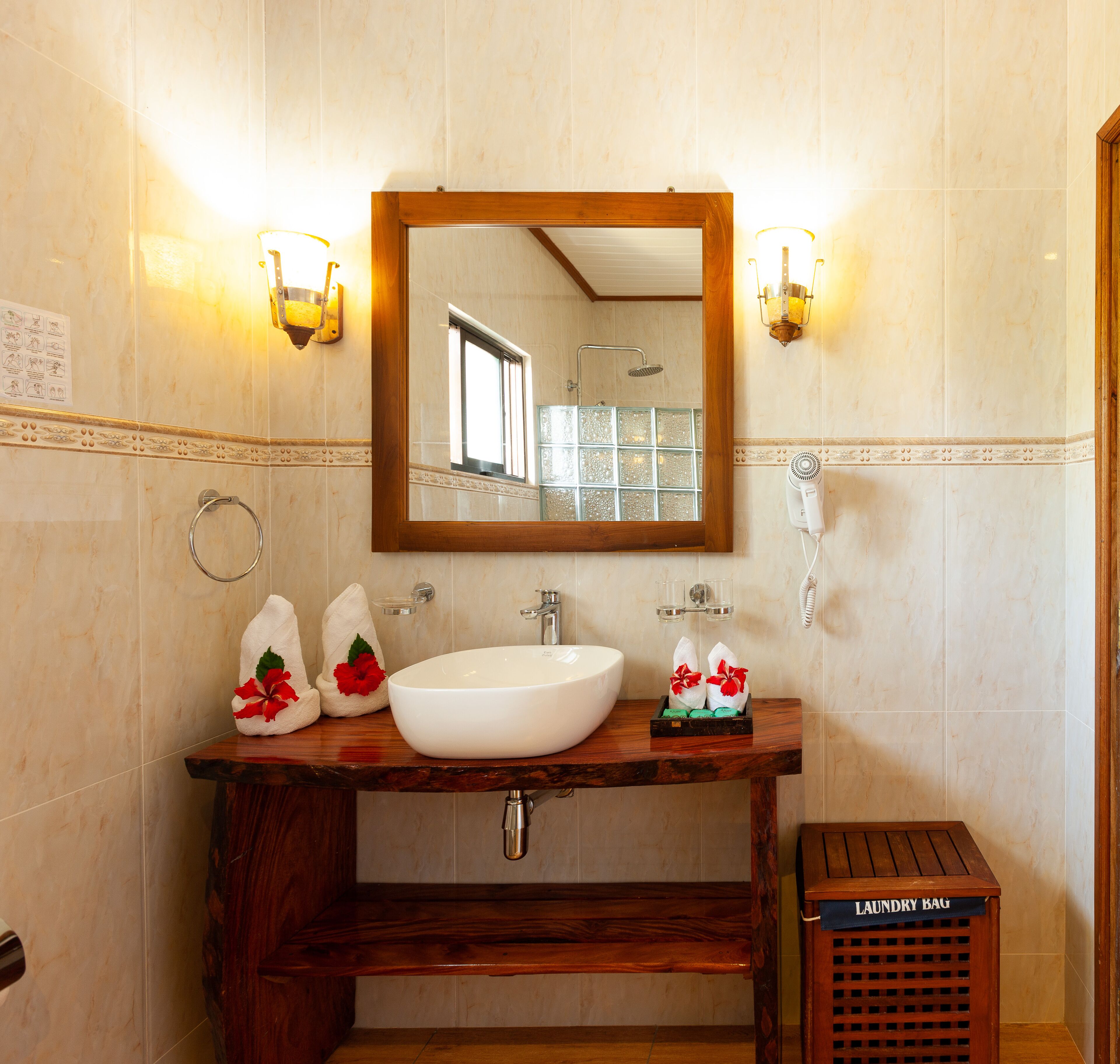 A bathroom with a wooden vanity, a large mirror, a white sink, and two wall-mounted lights.