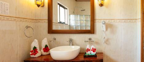 A bathroom with a wooden vanity, a large mirror, a white sink, and two wall-mounted lights.