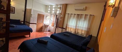 A hotel room with two beds, a bathroom, and a small sitting area.