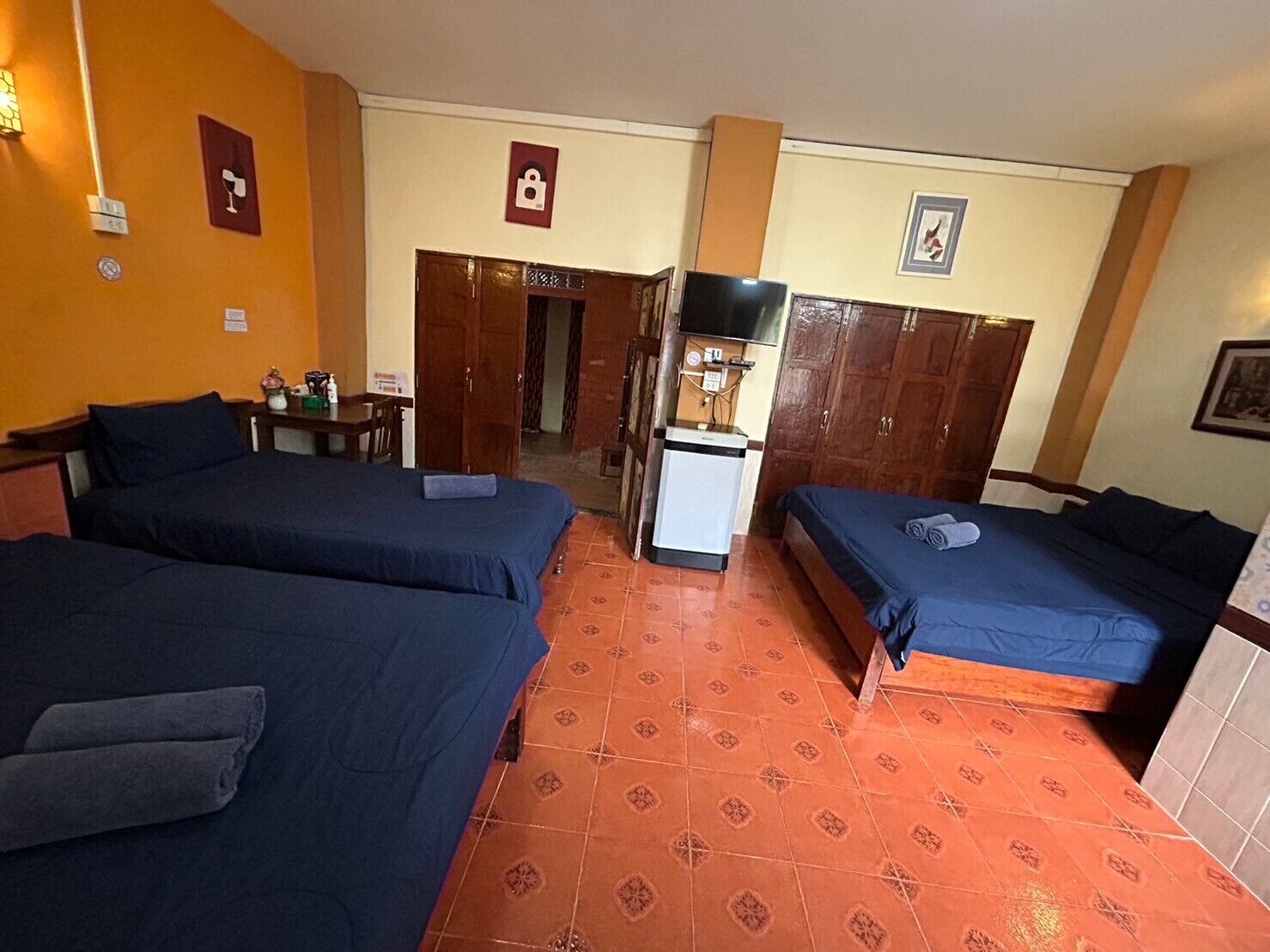 Habitación de hotel con dos camas, un escritorio pequeño, un refrigerador y una televisión.