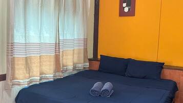 Ein Schlafzimmer mit Bett, Vorhängen, einer Klimaanlage und einem an der Wand hängenden Bild.