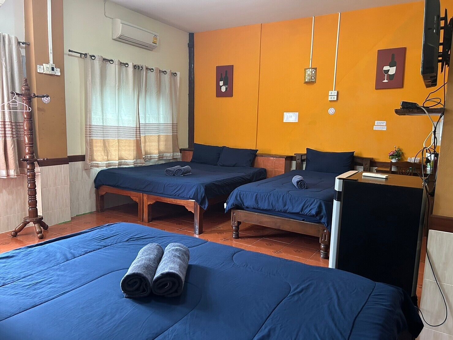 Ein Hotelzimmer mit zwei Betten, einem Schreibtisch, einem Fernseher und einem Fenster mit Vorhängen.
