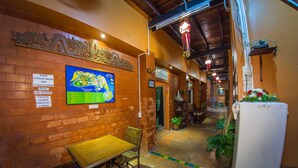 A corridor with a brick wall, a map, a table with chairs, and a refrigerator. - Baan Are Gong Riverside Homestay (Ayutthaya)