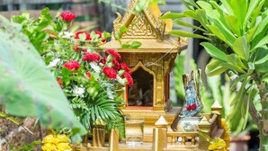 A small, ornate structure with a golden roof, surrounded by lush greenery and vibrant flowers. - Baan Are Gong Riverside Homestay (Ayutthaya)