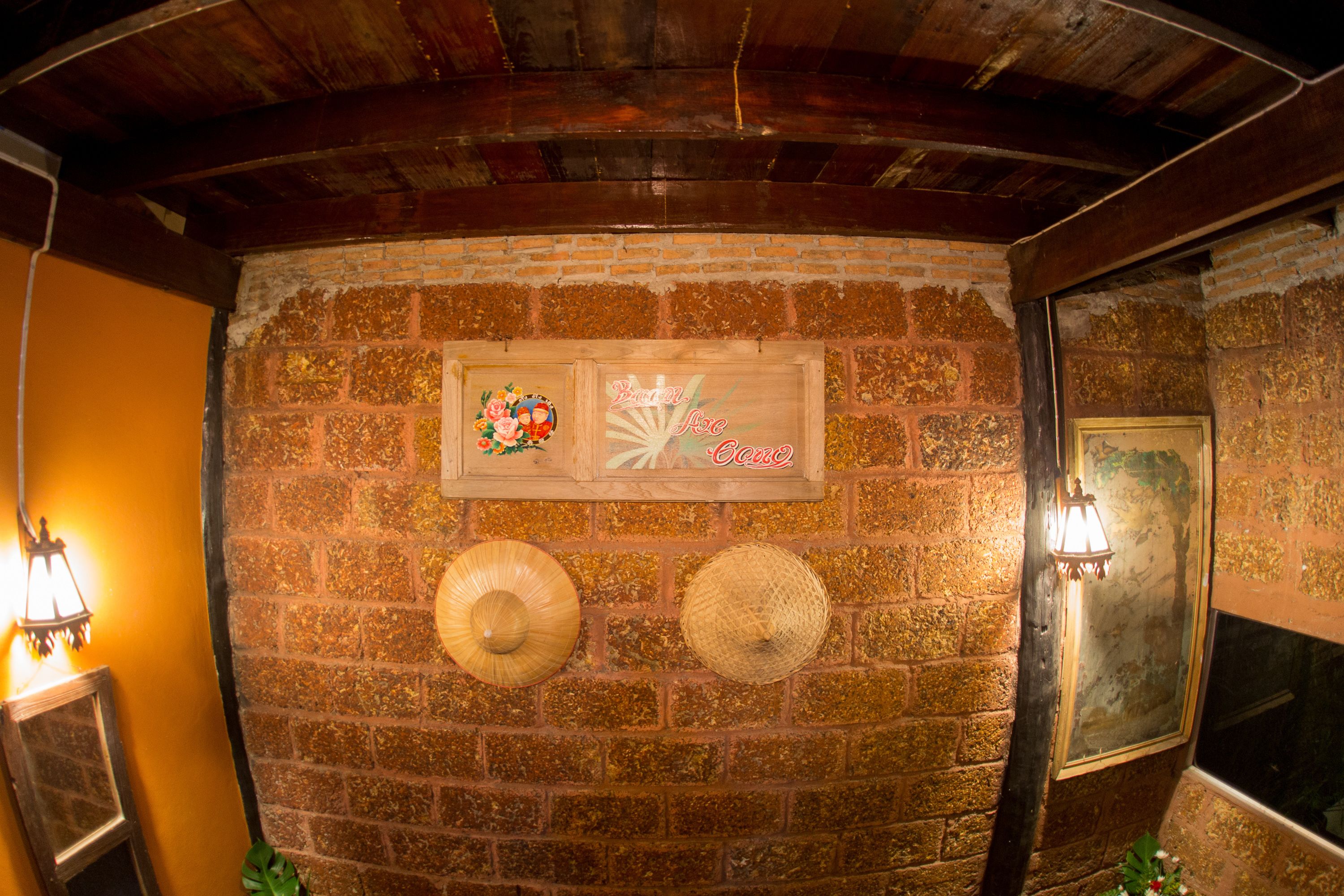 A brick wall with two woven hats and a wooden sign with text.