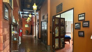 A corridor with tiled flooring, hanging lanterns, a bench, and a door with a glass panel. - Baan Are Gong Riverside Homestay (Ayutthaya)