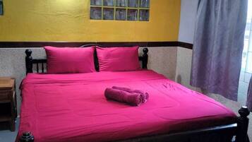 Un letto con una coperta e dei cuscini rosa acceso, una testiera in legno e una finestra con tende.