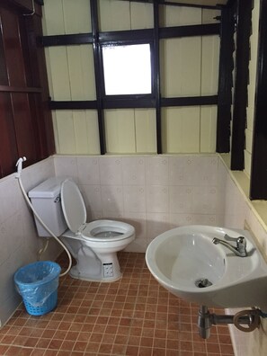 Un baño con inodoro, lavamanos y un cubo de basura azul.