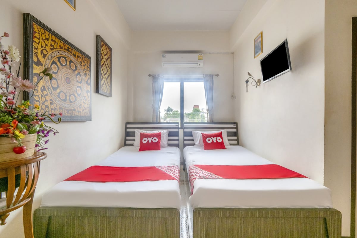 Une chambre d’hôtel avec deux lits, une télévision, un climatiseur et une fenêtre avec des rideaux.