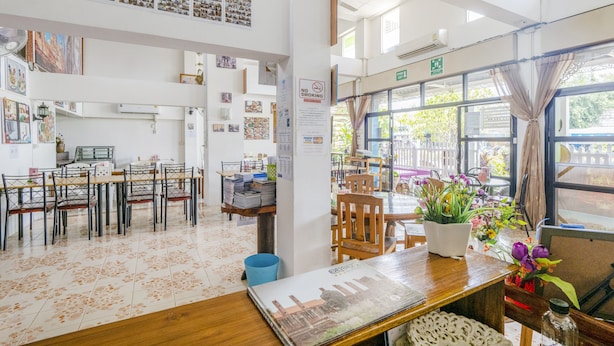 A spacious dining area with high ceilings, large windows, and a variety of seating arrangements. - Bann One Love (Ayutthaya)