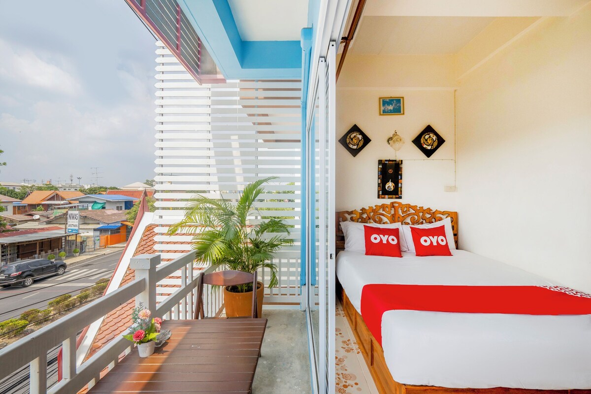 A balcony with a wooden floor, a potted plant, and a view of the street.