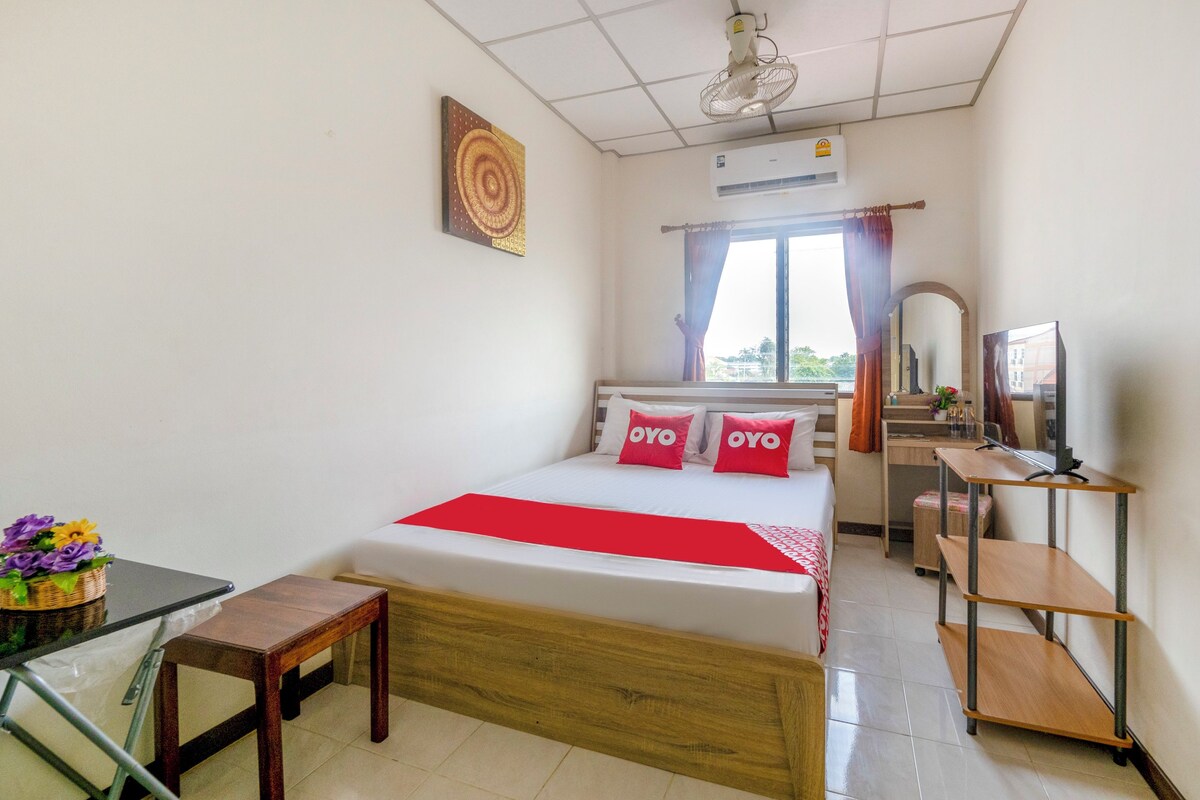 Une chambre d’hôtel avec un lit, un bureau, une chaise, une télévision et une fenêtre avec des rideaux.