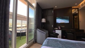 A hotel room with a bed, a TV, a desk, and a balcony with a table and chairs. - Sama Inn Hotel (Riyadh)