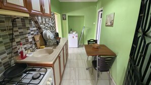 Une cuisine de taille réduite comprenant une cuisinière, un évier et un coin repas avec une table et des chaises.