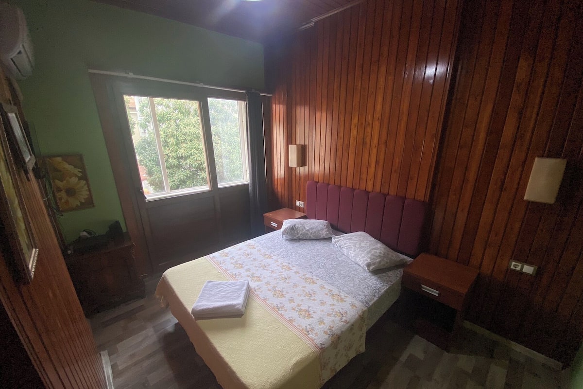 Una habitación con cama, paneles de madera, una ventana y una puerta.