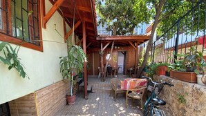 Une terrasse en bois avec une table et des chaises, un vélo et des plantes en pot.