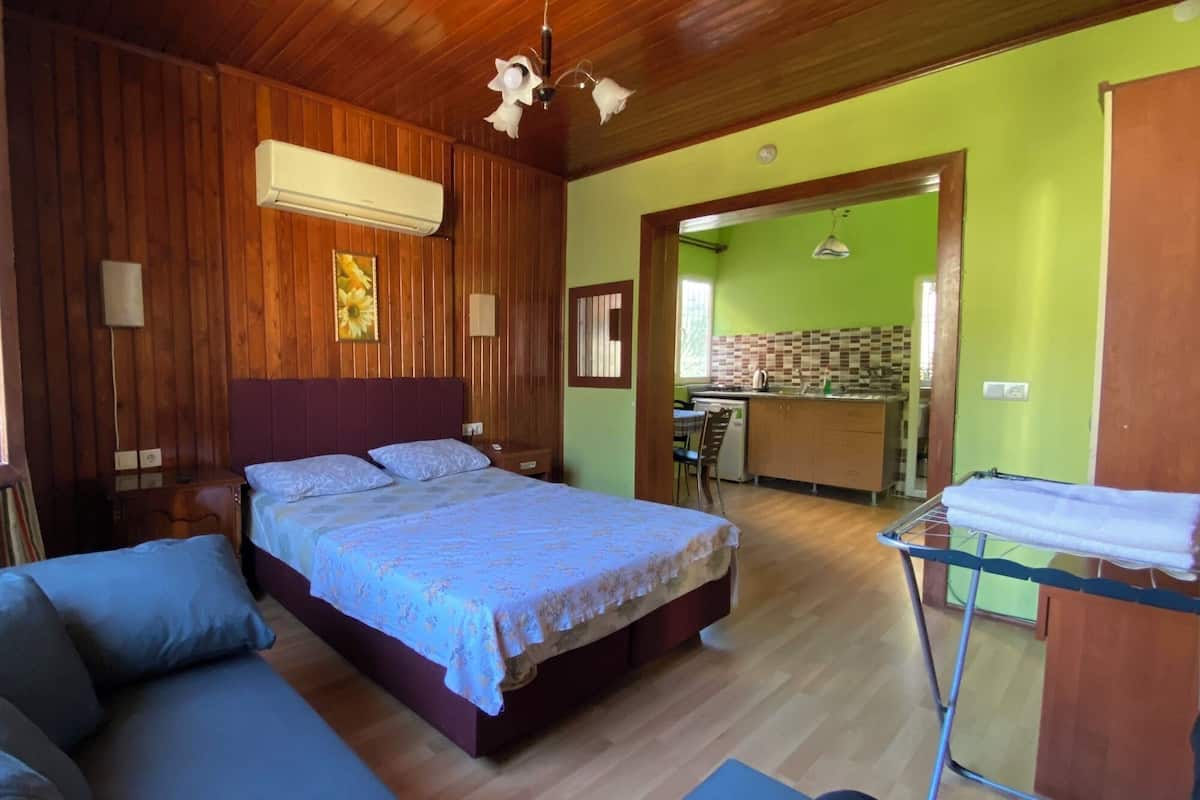 Un dormitorio con cama, techo de madera, ventana y vista a una cocina.