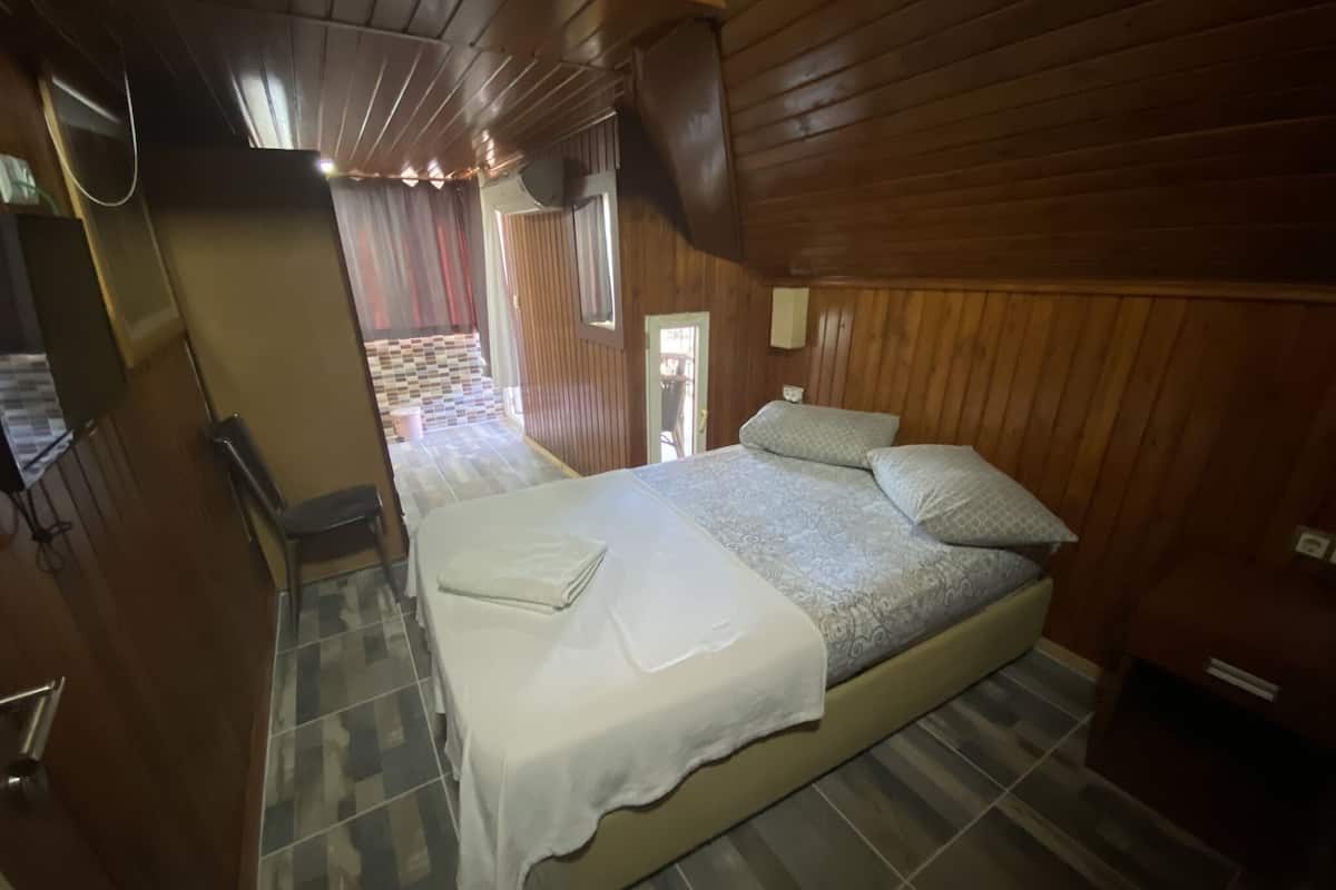 Una habitación de cabaña de madera con una cama, una silla y una mesita.