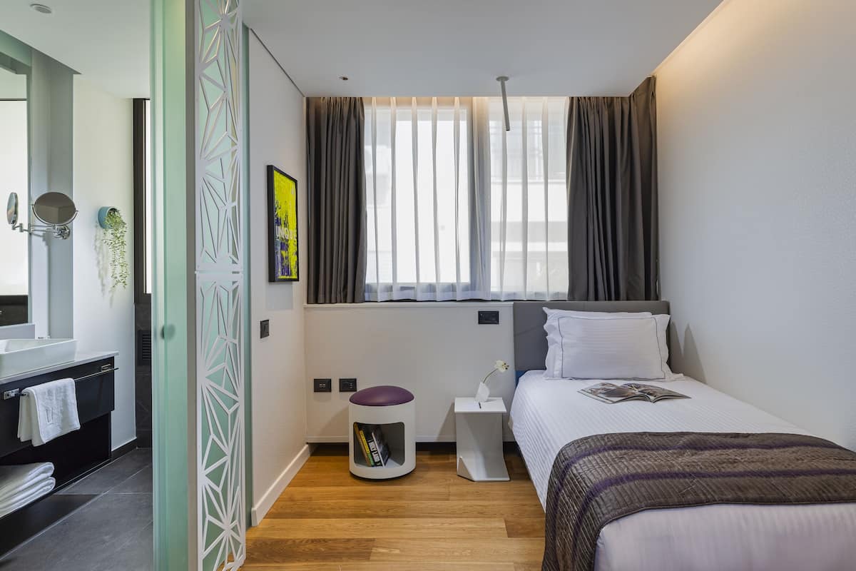 Ein modernes Schlafzimmer mit einem Bett, Nachttisch und einem Fenster mit Vorhängen.