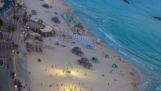 Eine Vogelperspektive zeigt einen Strand mit einem Volleyballfeld, Sonnenschirmen und Badegästen.