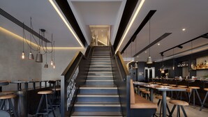 Eine moderne Treppe in einem Restaurant mit Barplätzen und einem Barbereich im Hintergrund.
