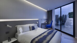 Ein modernes Hotelzimmer mit einem großen Bett, einem Nachttisch und Blick ins Freie.